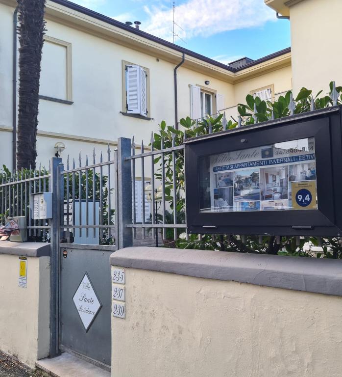 a television in front of a building with a fence at Villa Sante Residence in Pesaro