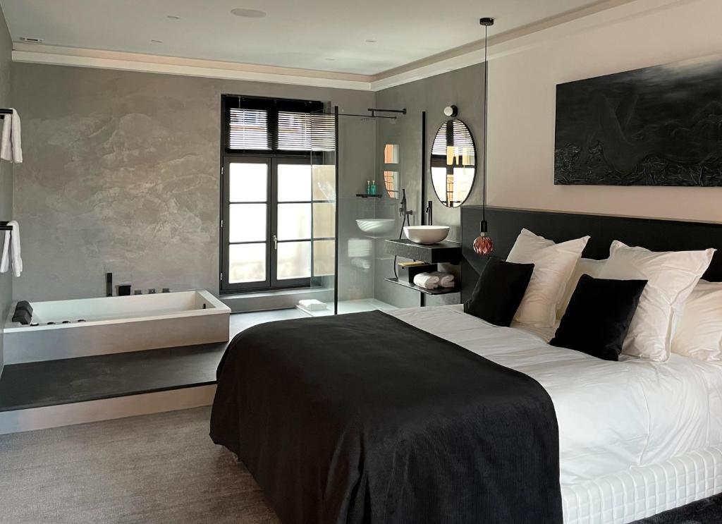 - une chambre avec un grand lit et une baignoire dans l'établissement Ennéa - Jacuzzi & Luxury Suites, à Perpignan