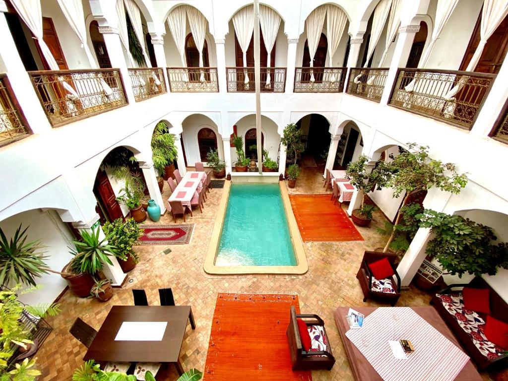 une piscine intérieure dans un bâtiment avec tables et chaises dans l'établissement Riad Mandalay, à Marrakech