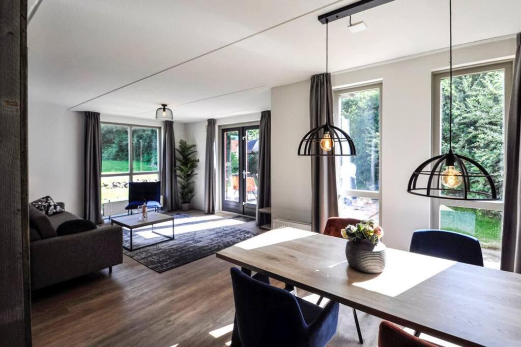 een woonkamer met een houten tafel en stoelen bij Tof wellness huis, alles nieuw, gelegen bij meer. in Ewijk
