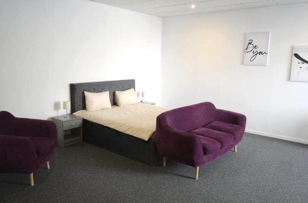 a bedroom with a bed and a purple chair at Luana Airport Apartments #6 in Otopeni