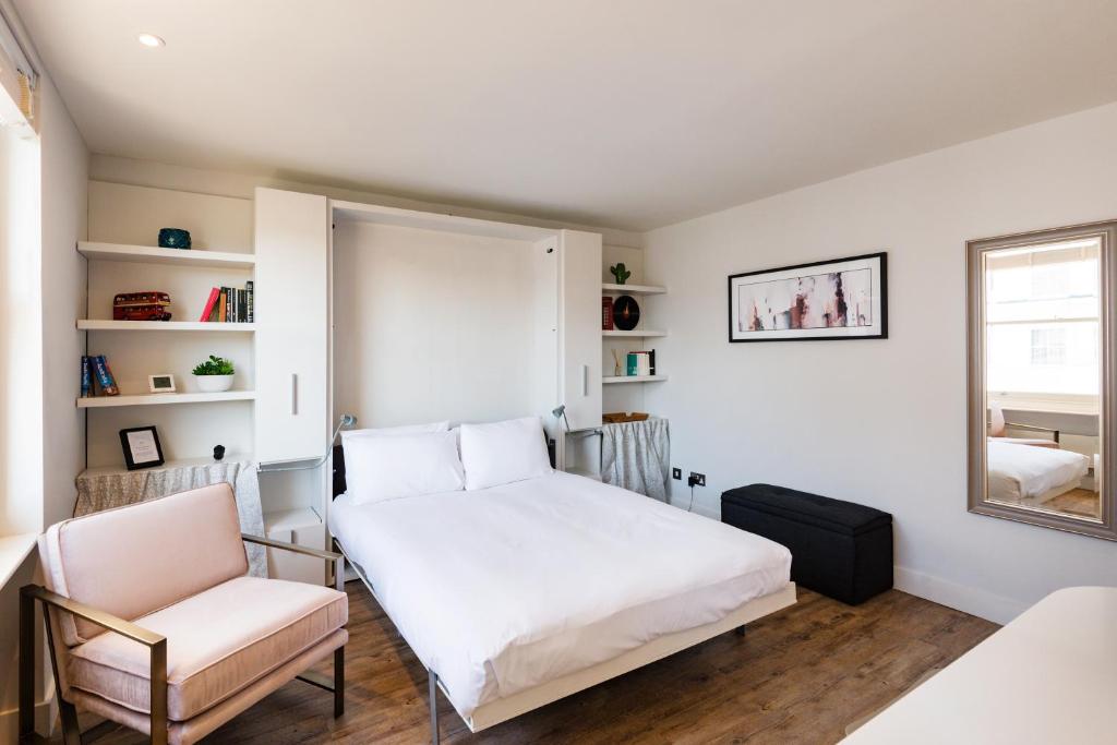 a bedroom with a bed and a chair and a window at Brand new studio flat in the heart of Notting Hill in London