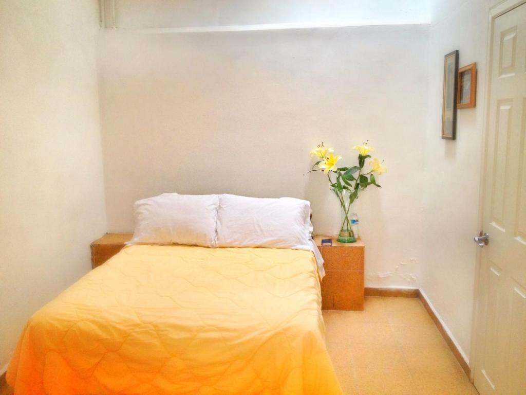 sypialnia z łóżkiem i wazonem kwiatów w obiekcie Hotel RJ Querétaro w mieście Querétaro