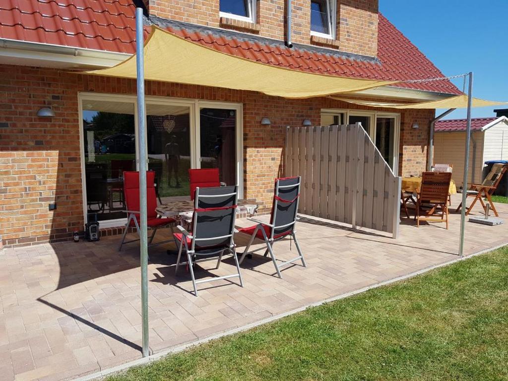 eine Terrasse mit Stühlen und einem Tisch vor einem Haus in der Unterkunft NEU! Ferienhaus Sonnenschein am Badesee in Aurich