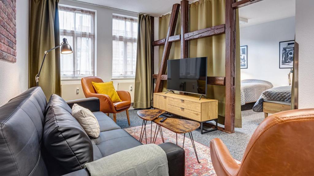 - un salon avec un canapé et une télévision dans l'établissement Pressehaus Apartment Steinweg, à Mühlhausen