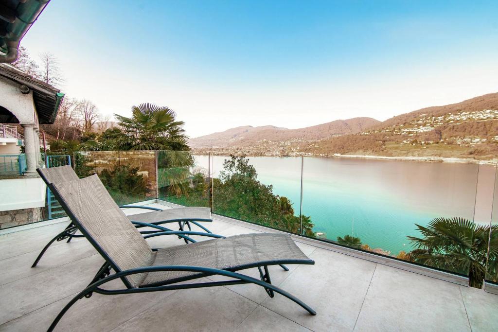two chairs on a balcony with a view of a lake at La Palma 2 by Quokka 360 - spacious flat with lake view in Montagnola