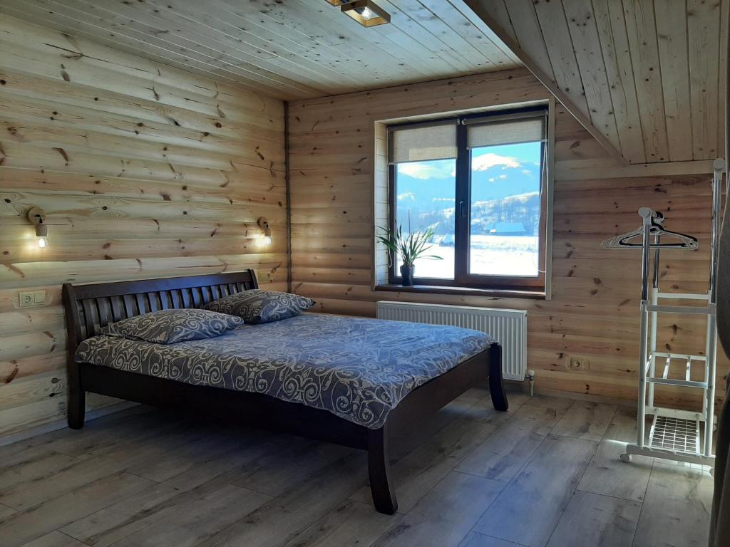 una camera da letto con letto in una camera in legno di У Мирослави a Pilipets