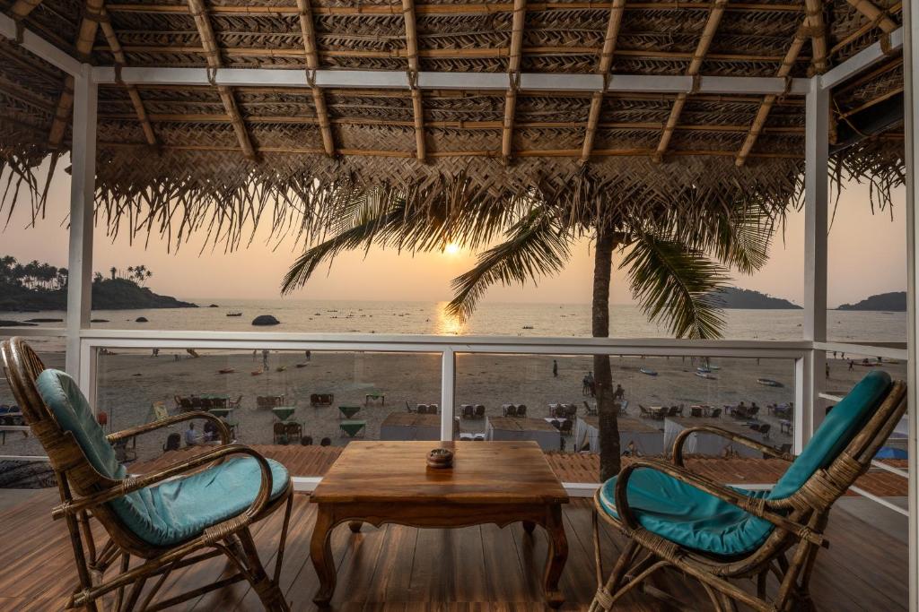 uma mesa e cadeiras num alpendre com praia em The Shore beach resort Palolem em Canacona