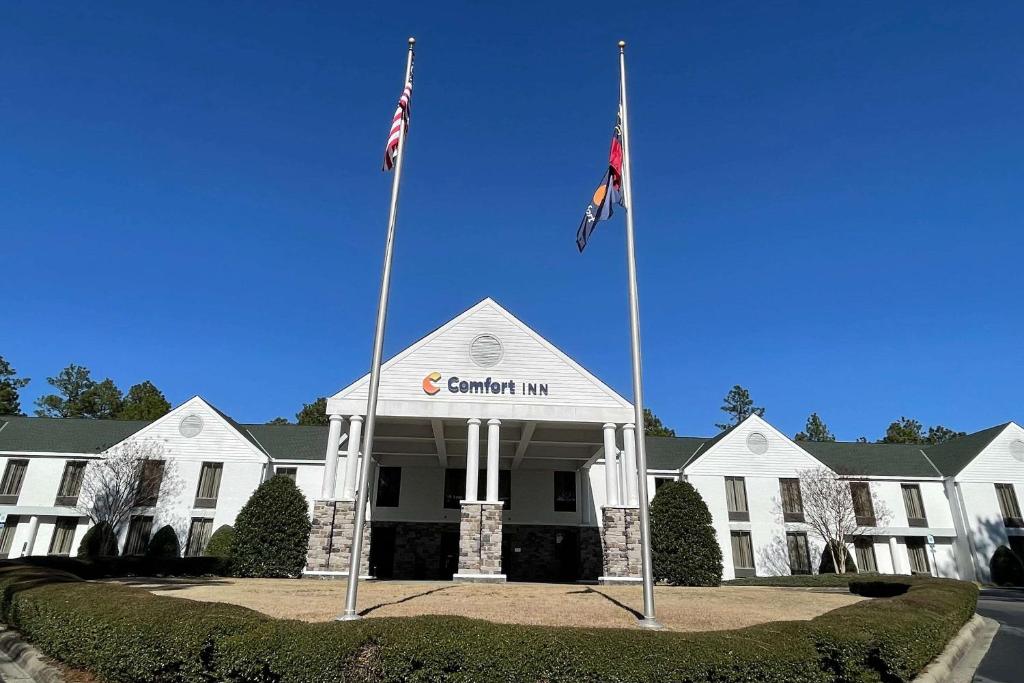 dos banderas en postes frente a un edificio blanco en Comfort Inn, en Pinehurst