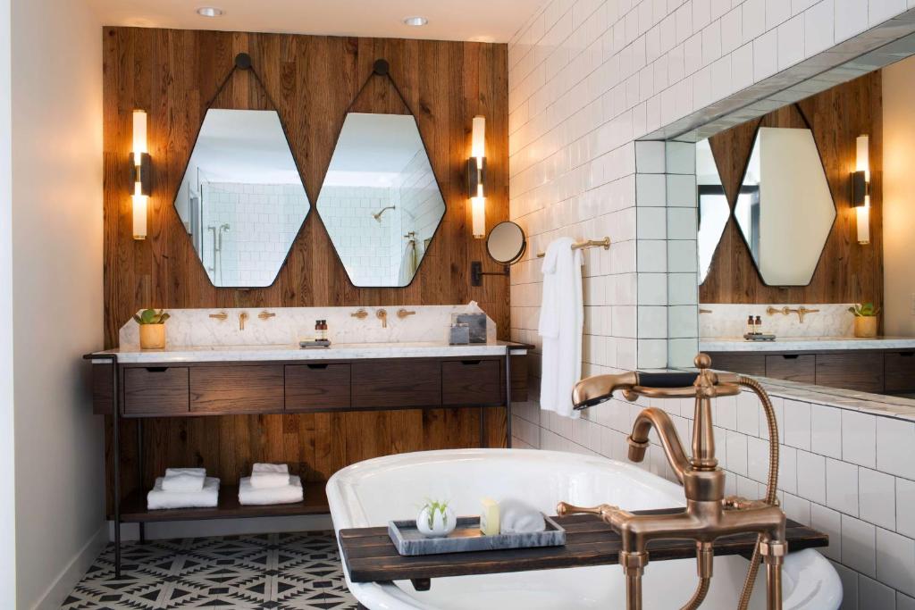 a bathroom with a tub and a sink and mirrors at Thompson Nashville, by Hyatt in Nashville