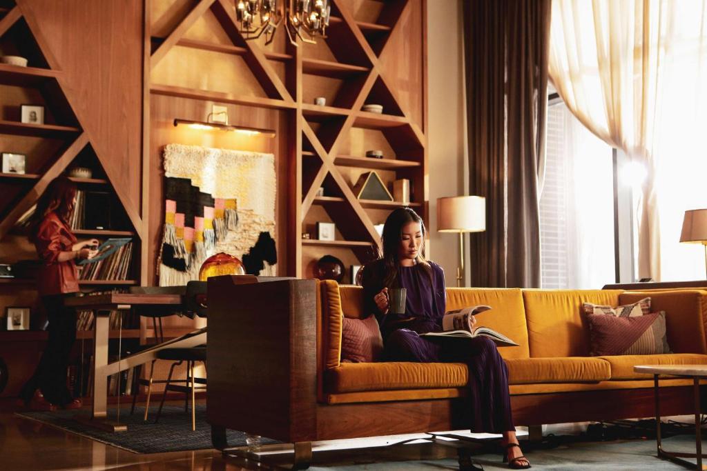 a woman sitting on a couch in a living room at Thompson Nashville, by Hyatt in Nashville