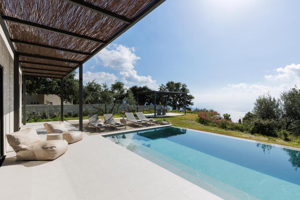 a swimming pool with lounge chairs and a house at Paloubi Estate in Sinarádes