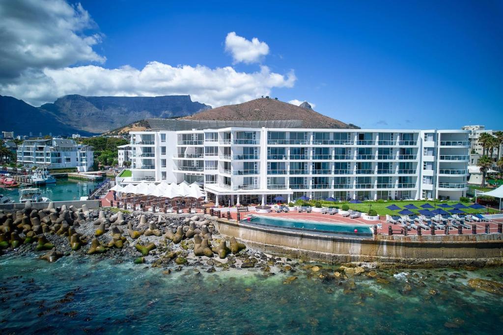 a large hotel with a pool and a body of water at Radisson Blu Hotel Waterfront, Cape Town in Cape Town