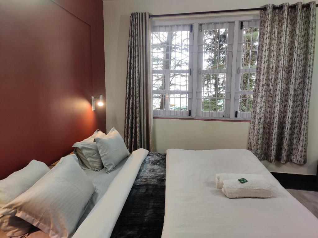 1 dormitorio con 2 camas y ventana en Shree Guest House, en McLeod Ganj
