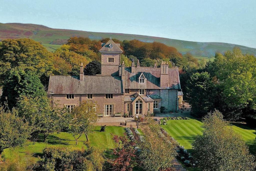 an old house on a hill with trees and grass at The Casterton Grange Estate in Kirkby Lonsdale