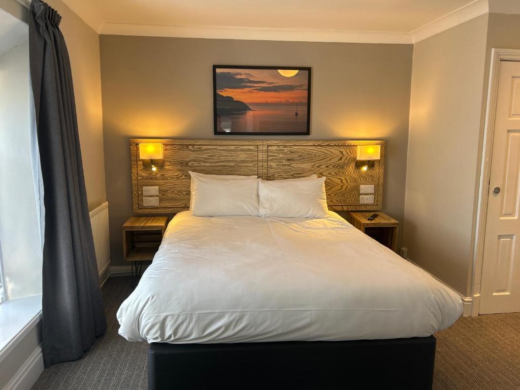 a bedroom with a large white bed with a wooden headboard at Hotel Penwig in New Quay