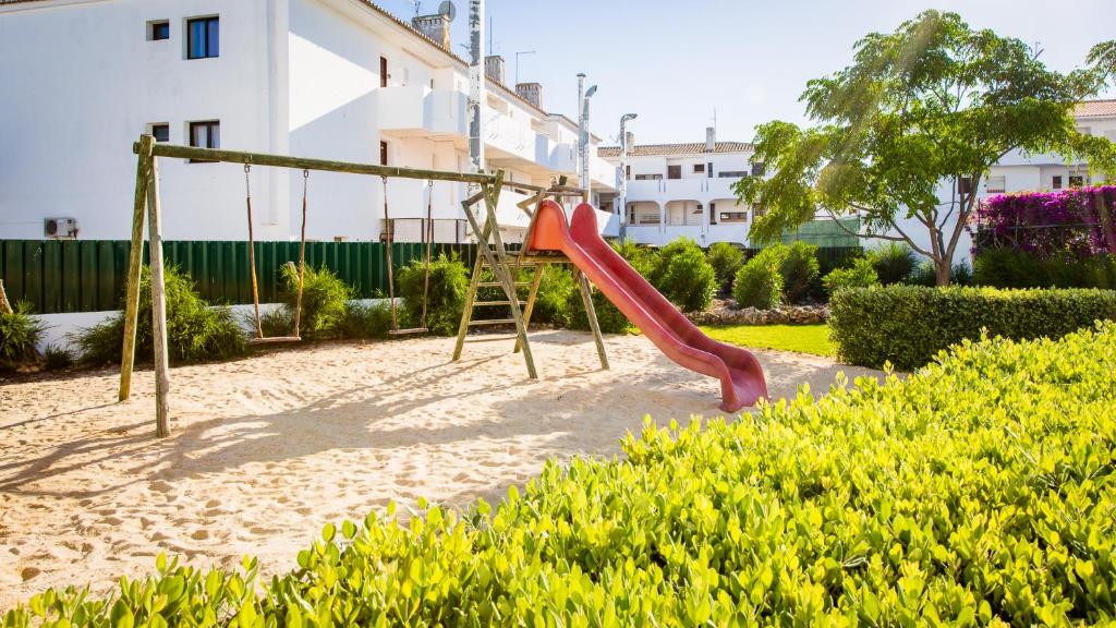 un parque infantil con columpio en un jardín en Central Albufeira Great Location, 