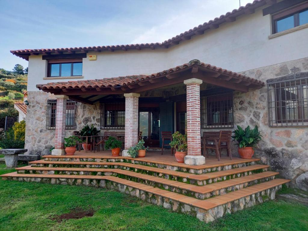 una casa con una escalera que conduce al porche delantero en La Cirujana de Gredos, en San Esteban del Valle