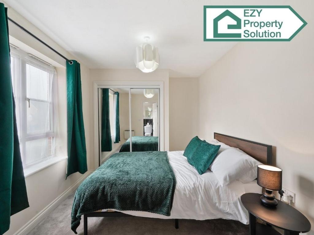 ein Schlafzimmer mit einem Bett mit einer grünen Decke in der Unterkunft Stylish 2 bed Apt - Free Parking in Thamesmead