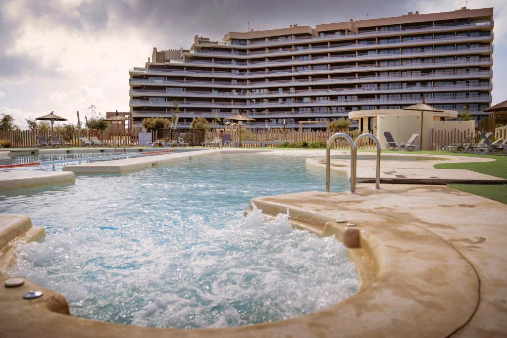 a swimming pool in front of a large hotel at Los Flamencos - Playa Paraíso - Calle Bomilcar in Cartagena