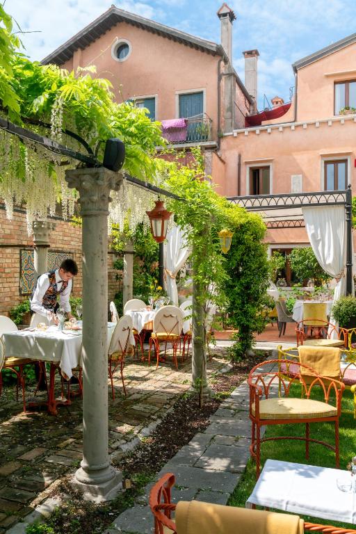 a man sitting at a table in a garden at Excess Venice Boutique Hotel & Private Spa - Adults Only in Venice
