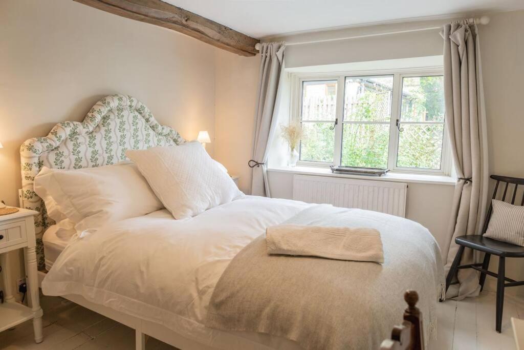 1 dormitorio con cama blanca y ventana en Charming Country Cottage Near Nailsworth en Box