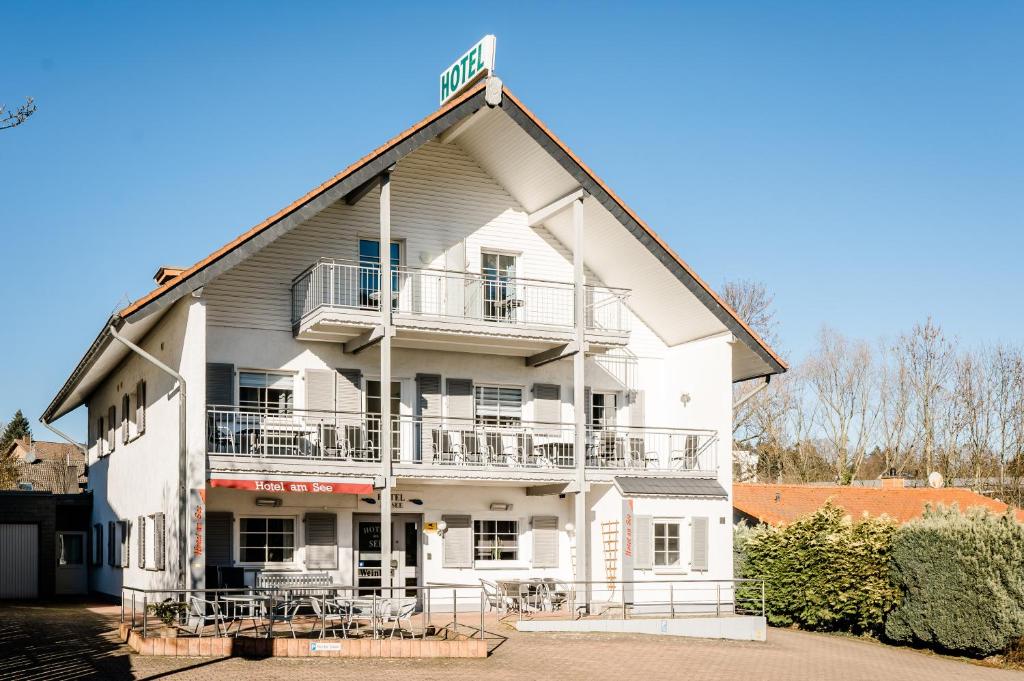 Großes weißes Gebäude mit Balkon in der Unterkunft Hotel am See in Kreuzau