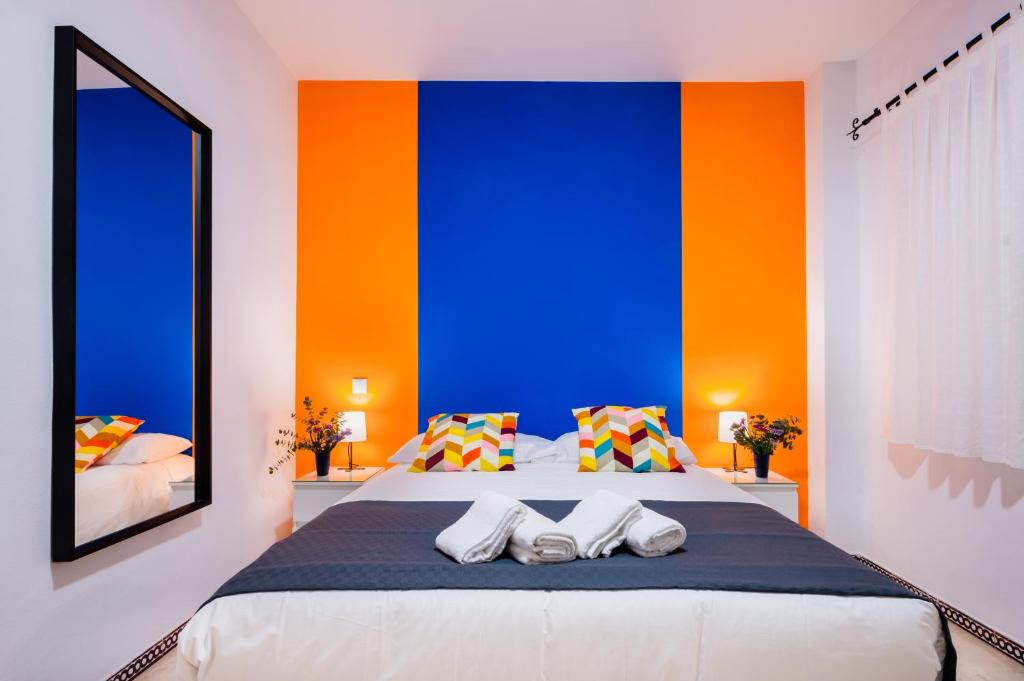 ein Schlafzimmer mit einer blauen und orangefarbenen Wand in der Unterkunft Anfitrión Sevilla 6 in Sevilla