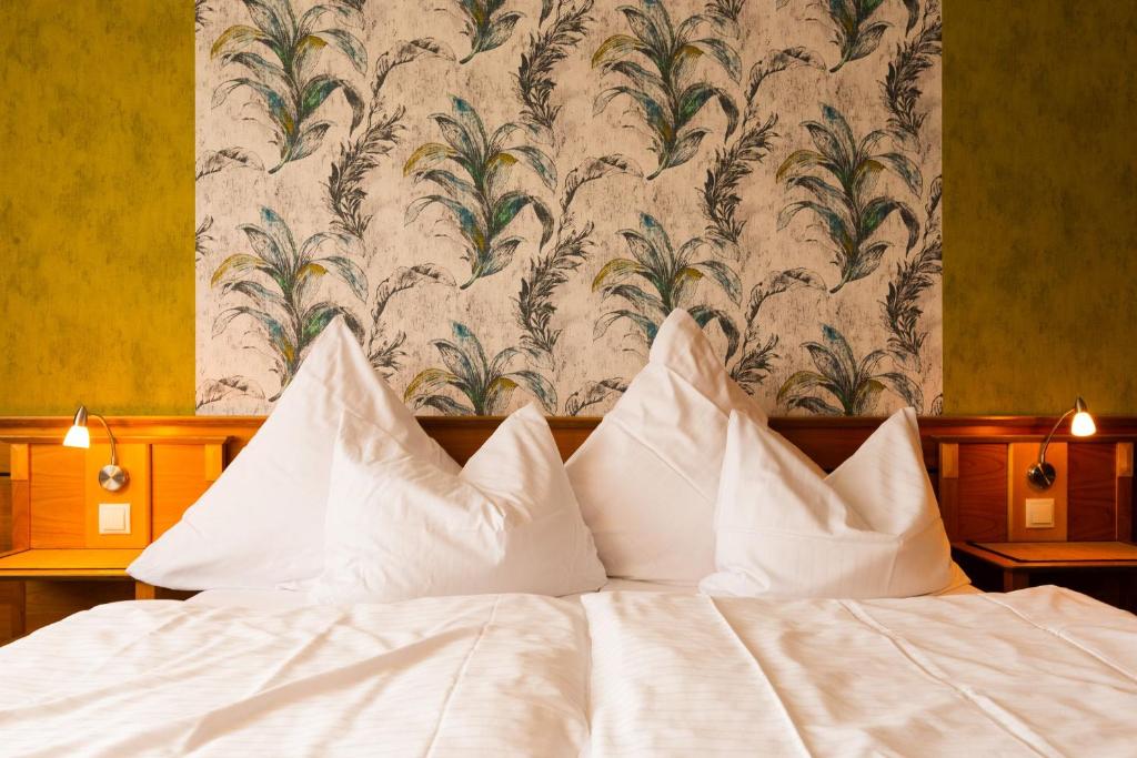 a bed with white pillows in front of a wallpaper at Biobausewein WEIN HOTEL LEBEN in Iphofen