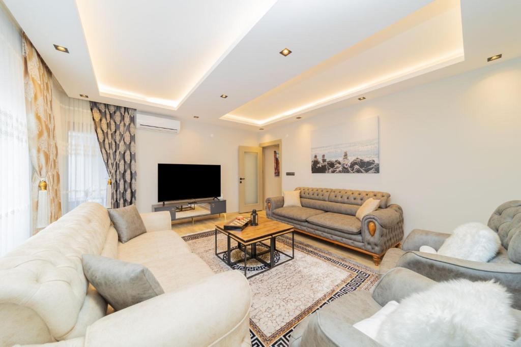 a living room with couches and a flat screen tv at Comfy Flat with Balcony Close to Konyaalti Beach in Antalya