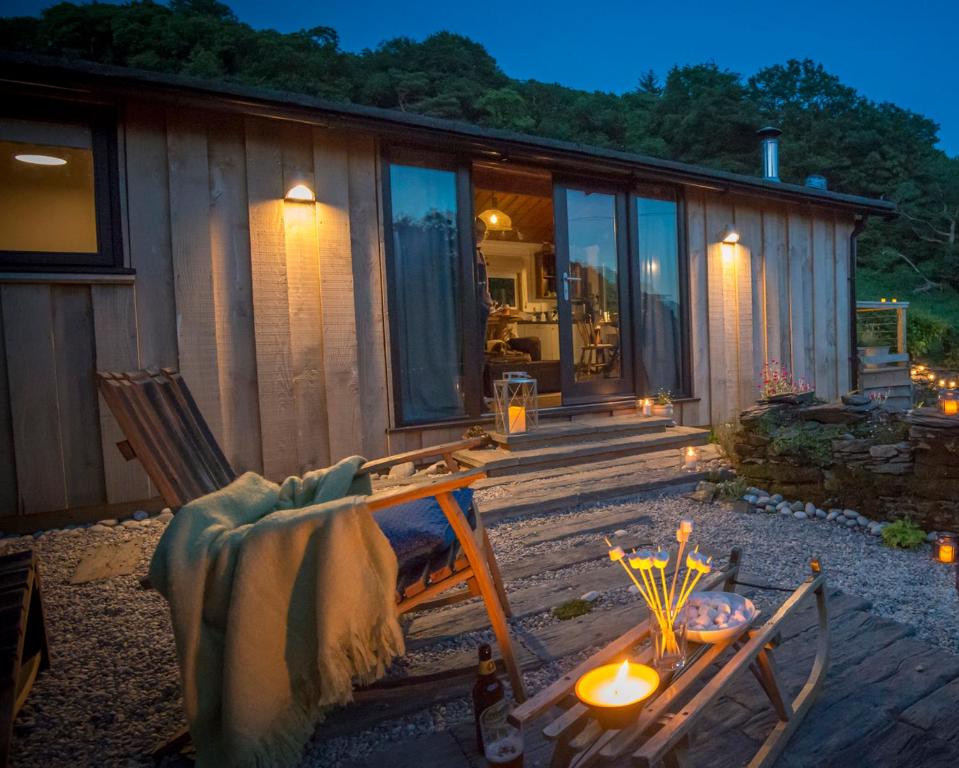 una cabaña con mesa y sillas frente a ella en Little Kestrel Cabin en Pennal