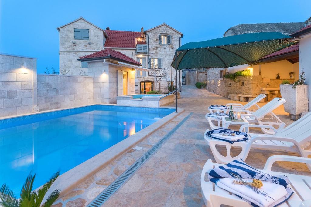 una villa con piscina e sedie a sdraio di Family friendly house with a swimming pool Skrip, Brac - 17345 a Postira (Postire)