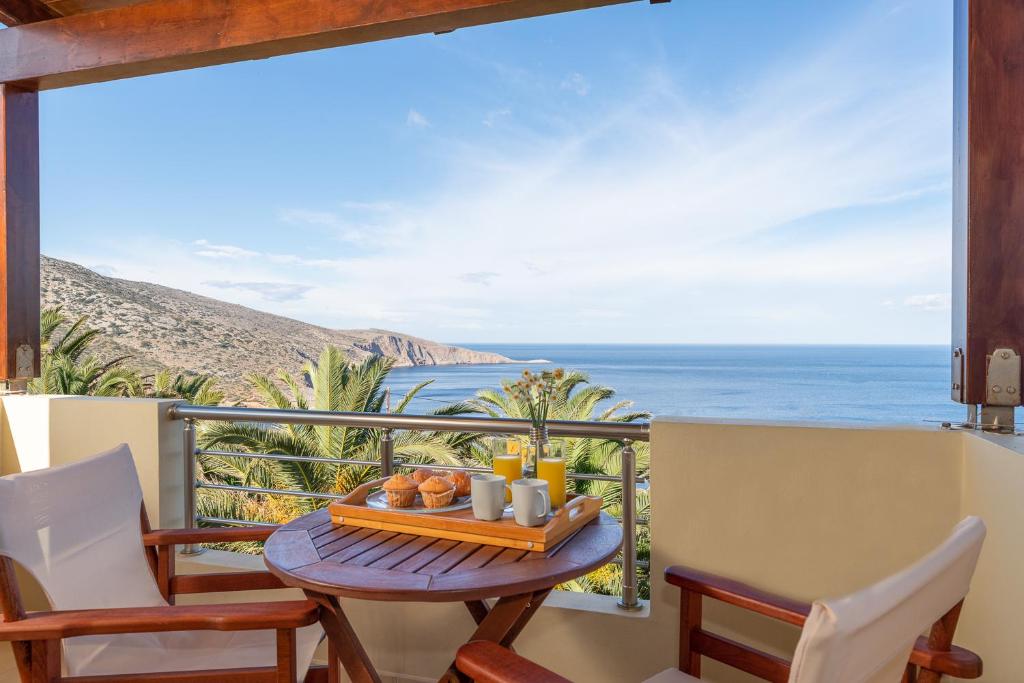 a table on a balcony with a view of the ocean at Vitamin Sea Panoramic Villas in Agia Pelagia
