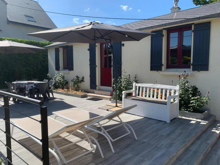 eine Terrasse mit Sonnenschirm und Tisch und Stühlen in der Unterkunft Cottage les petites voiles plage in Agon Coutainville