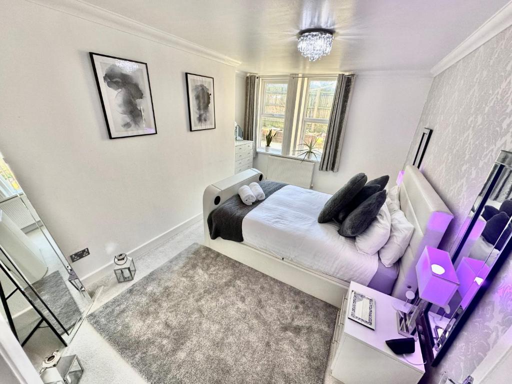- une chambre avec un lit blanc et des oreillers violets dans l'établissement Glen Fern Lodge - Garden Apartment with Parking - Heart of Town Centre - Close to Beach, à Bournemouth