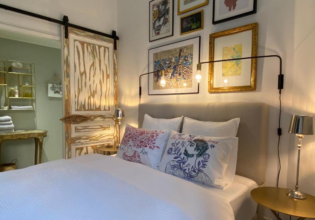 a bedroom with a white bed with paintings on the wall at Un palmier à sa fenêtre in Grasse