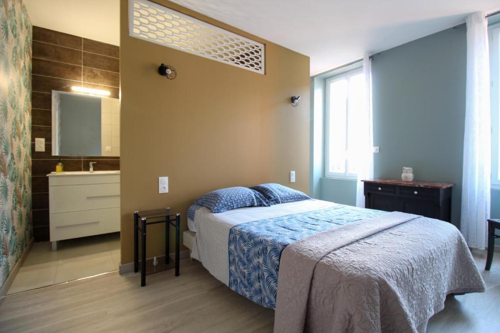 ein Schlafzimmer mit einem Bett und ein Badezimmer mit einem Waschbecken in der Unterkunft L'Ostalada in Albi