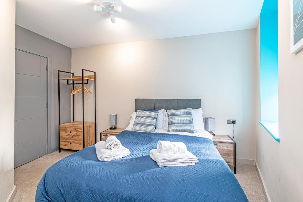 a bedroom with a blue bed with towels on it at Wigan Central Serviced Apartments in Wigan