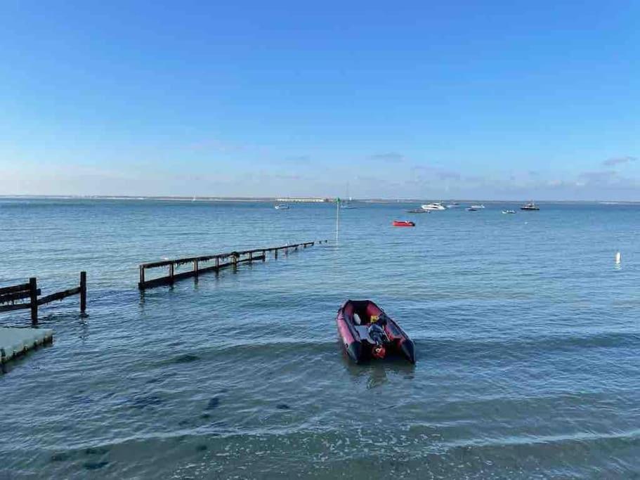 a small boat in the water next to a dock at Alma Court Retreat Freshwater IOW in Freshwater