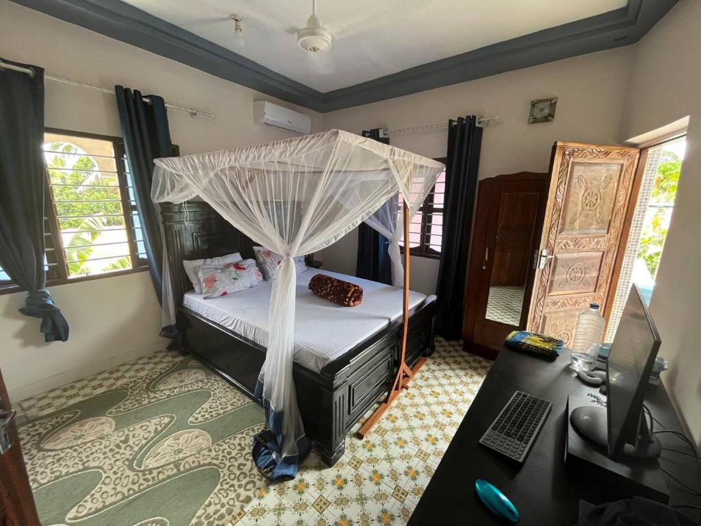 a bedroom with a bed with a mosquito net at Anayah House in Kiembi Samaki