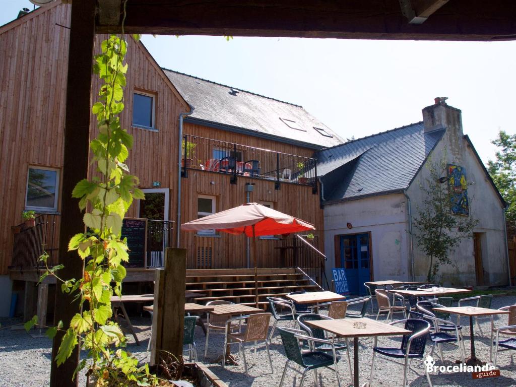 un patio esterno con tavoli e ombrelloni di fronte a un edificio di Auberge du Champ Commun ad Augan