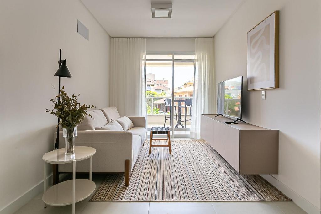 uma sala de estar branca com um sofá e uma mesa em Cannes Club Residence a 200m da praia, recém inaugurado em Florianópolis