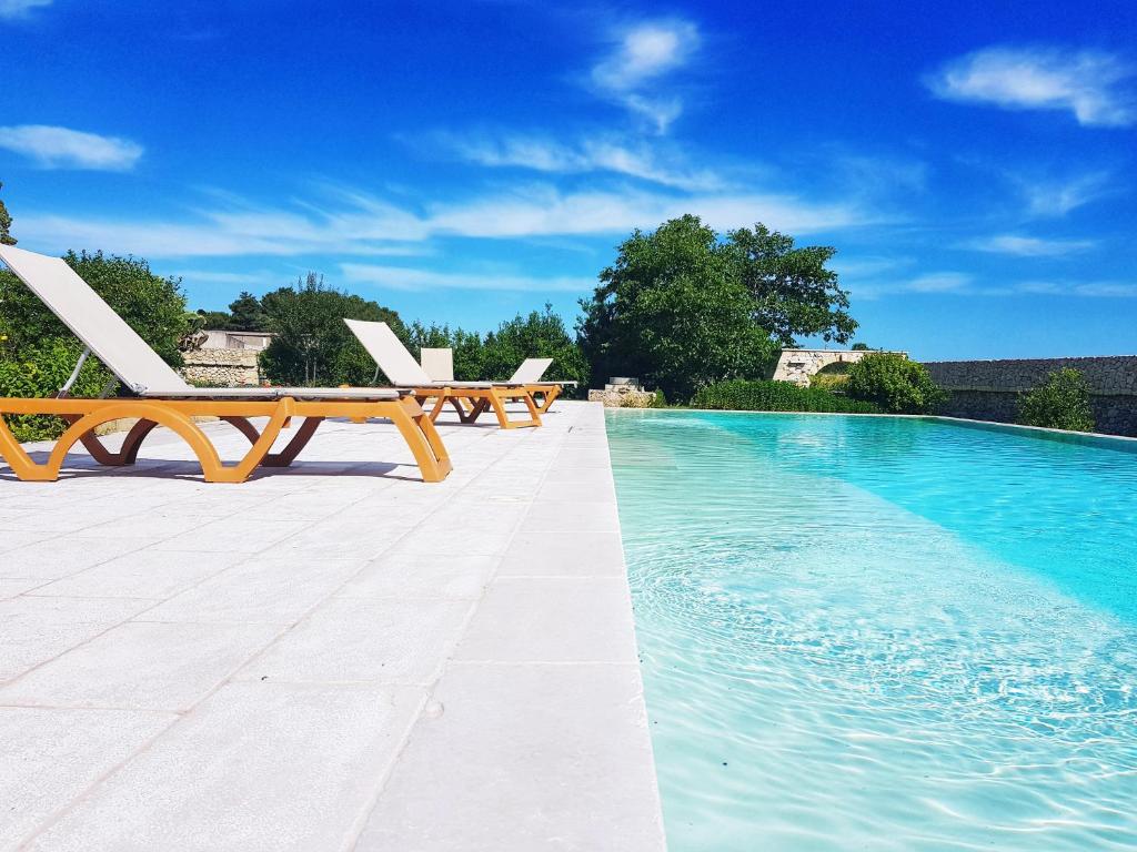 uma piscina com duas espreguiçadeiras e uma piscina em Masseria San Cosimo em Carpignano Salentino