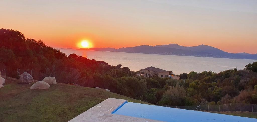 um pôr-do-sol sobre a água com uma piscina em CORSE HOLISTIKA - Rez-de-jardin avec vue mer exceptionnelle et piscine magnifique em Pietrosella