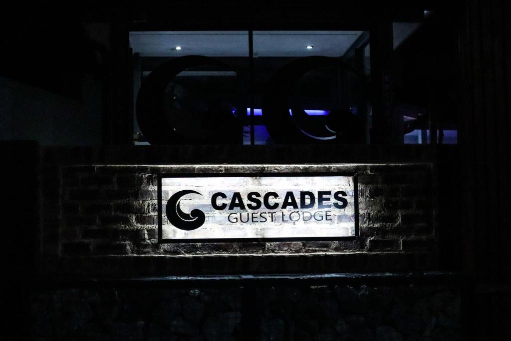 Cascades Guest Lodge في نيلسبروت: a sign that reads caspalos guestlege on a pick wall