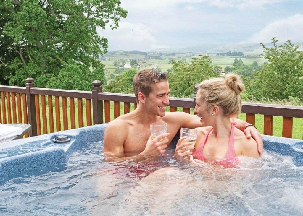 a man and a woman sitting in a hot tub at Nunland Hillside Lodges 