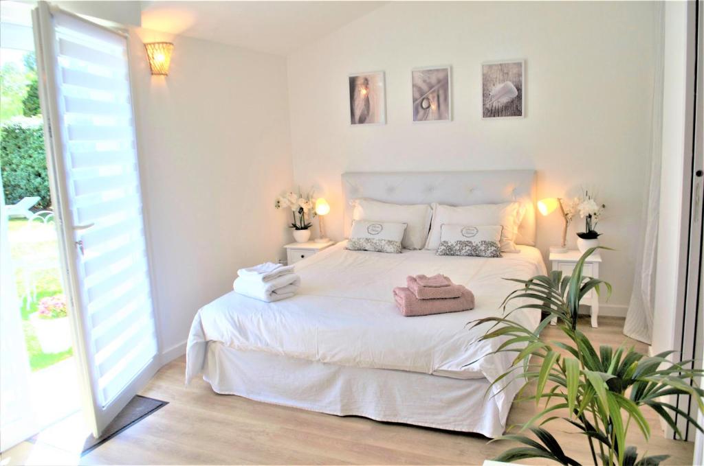 a white bedroom with a white bed and a window at Chambre d'hôtes de charme MERBLEUESOLEIL in Six-Fours-les-Plages