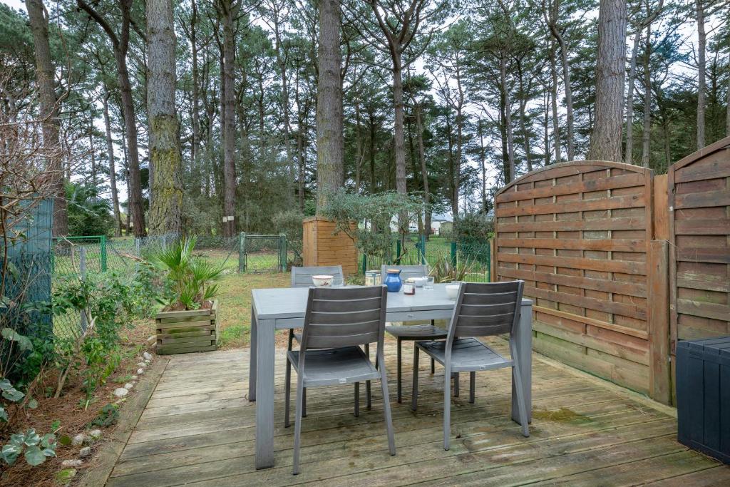una mesa y sillas en una terraza de madera con una valla en Maison a 150 metres de la mer au Pouliguen!, en Le Pouliguen