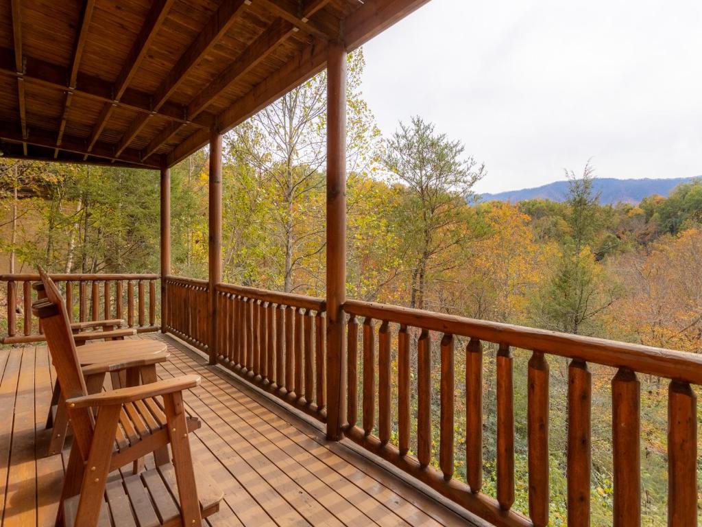 une véranda en bois avec un banc et une vue sur les bois dans l'établissement Changes in Latitude, 4 Bedroom, Sleeps 12, Private, View, Theater Room, à Gatlinburg