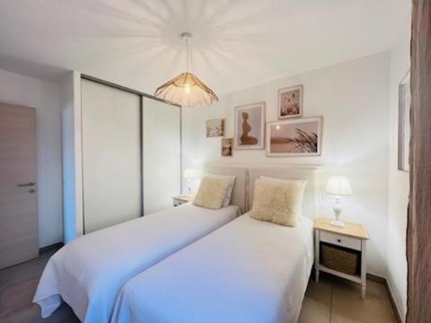 a bedroom with two beds and a chandelier at BEL'ORIZONTE C, 100m des plages et vue mer in Propriano